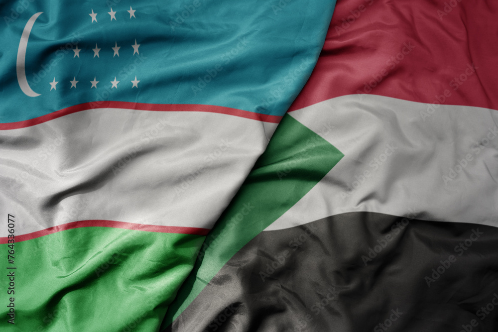 big waving national colorful flag of sudan and national flag of uzbekistan.