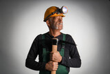 Mature miner man with pick axe on dark background