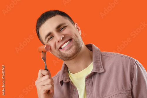 Young man with tasty sausag...