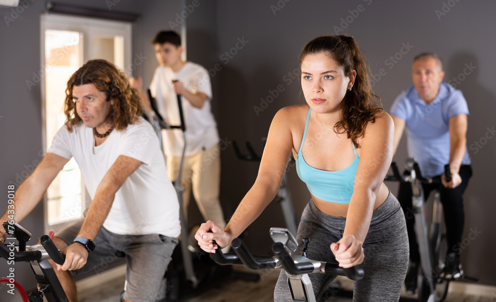 Focused motivated young girl leading healthy active lifestyle doing cardio workout on exercise bike in gym