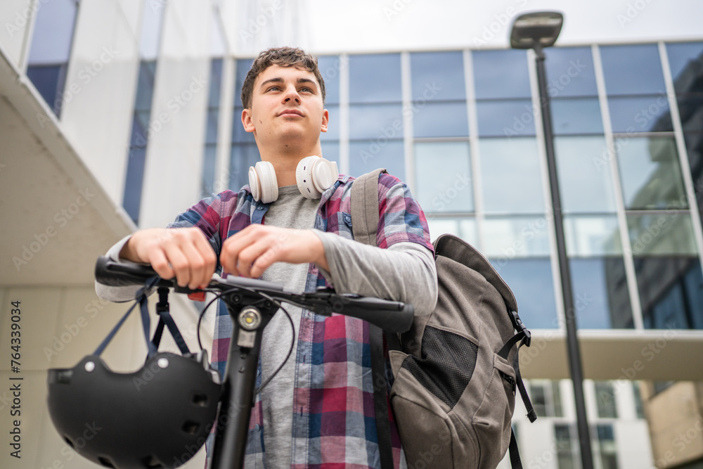 Young man caucasian teenager with electric kick push scooter in city Young man caucasian teenager with electric kick push scooter in city