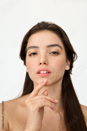 Young adult Latin woman, brunette gen z girl with freckles on face looking at camera posing for beauty vertical portrait isolated on white background. Skincare and cosmetic for young skin ads.