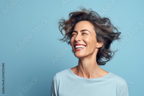 Portrait of a happy young woman with flying hair on blue background