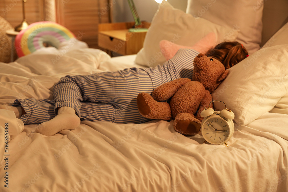 Adorable little girl with teddy bear and alarm clock sleeping in bed Adorable little girl with teddy bear and alarm clock sleeping in bed