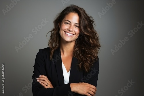 Portrait of a happy young business woman smiling with arms crossed over gray background