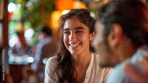 A woman is happily chatting with a Spanish friend at a restaurant during a meeting.