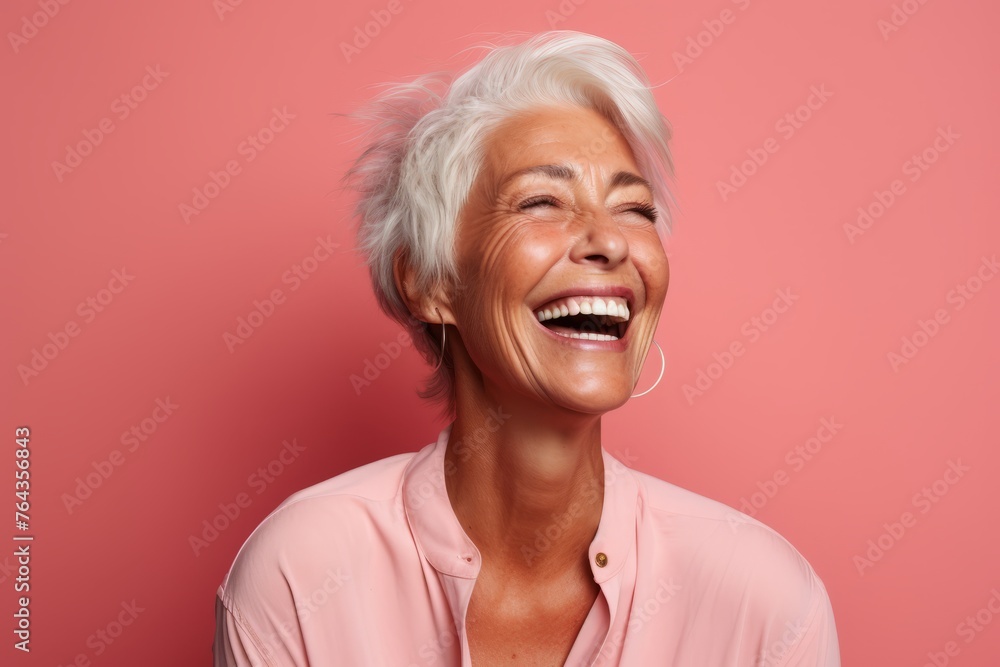 Portrait of a happy senior woman laughing and looking at camera against pink background Portrait of a happy senior woman laughing and looking at camera against pink background