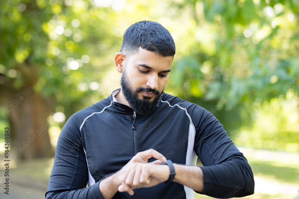 Active man checking fitness tracker in a park Active man checking fitness tracker in a park