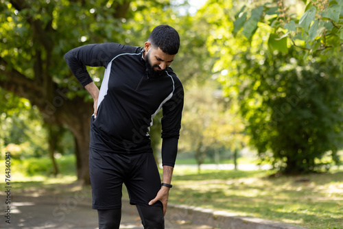 Male athlete suffering from lower back pain in park