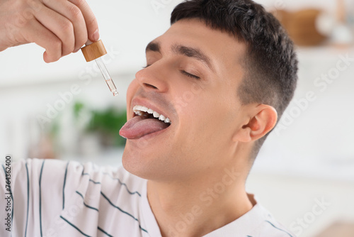 Young man taking CBD oil in...