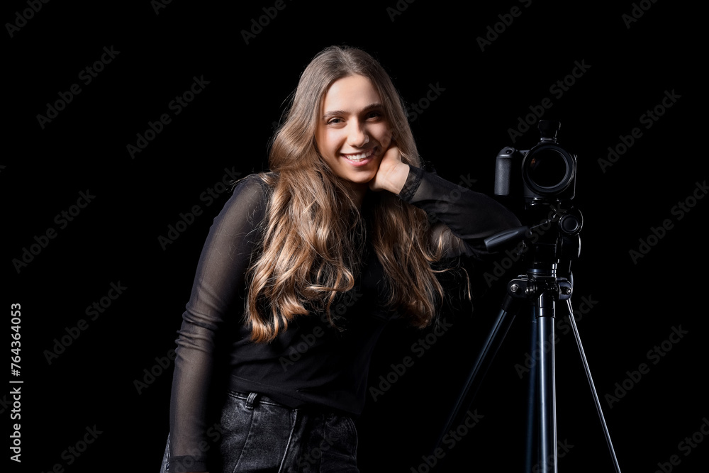 Portrait of female photographer with modern camera on tripod against black background Portrait of female photographer with modern camera on tripod against black background