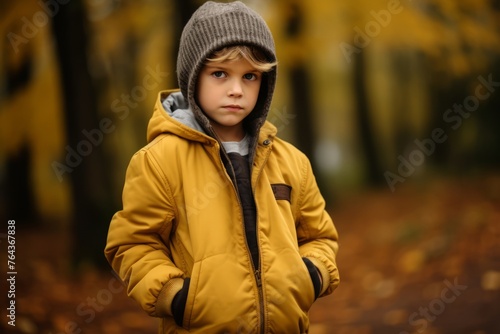 Portrait of a boy in a yellow jacket in the autumn forest.