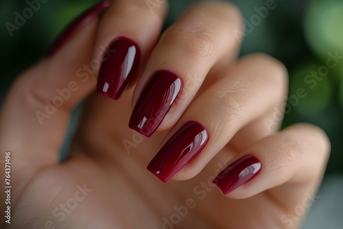A hand with four long  painted nails in a deep red color