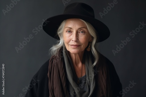 Portrait of a senior woman wearing hat and scarf on black background