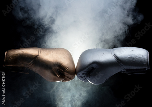 Two Boxing Glove in silver and gold punch hit together. Business challenge fighting concept. Smoke at back, black background isolated