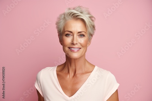 Portrait of happy senior woman with short hair over pink background.