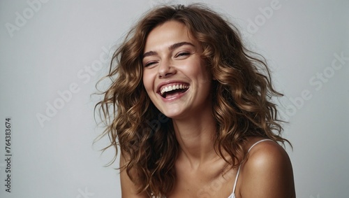 Russian woman in her 20s with beautiful wavy hair posing smilingly on a white background, studio shot, space for advertising photo