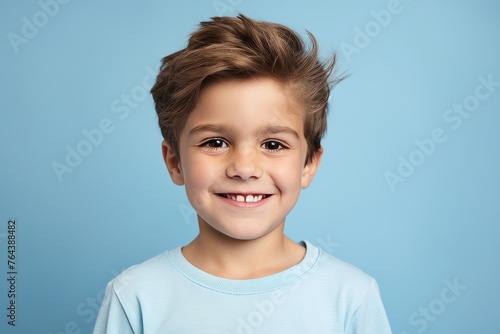 Portrait of cute little boy smiling at camera on blue background.