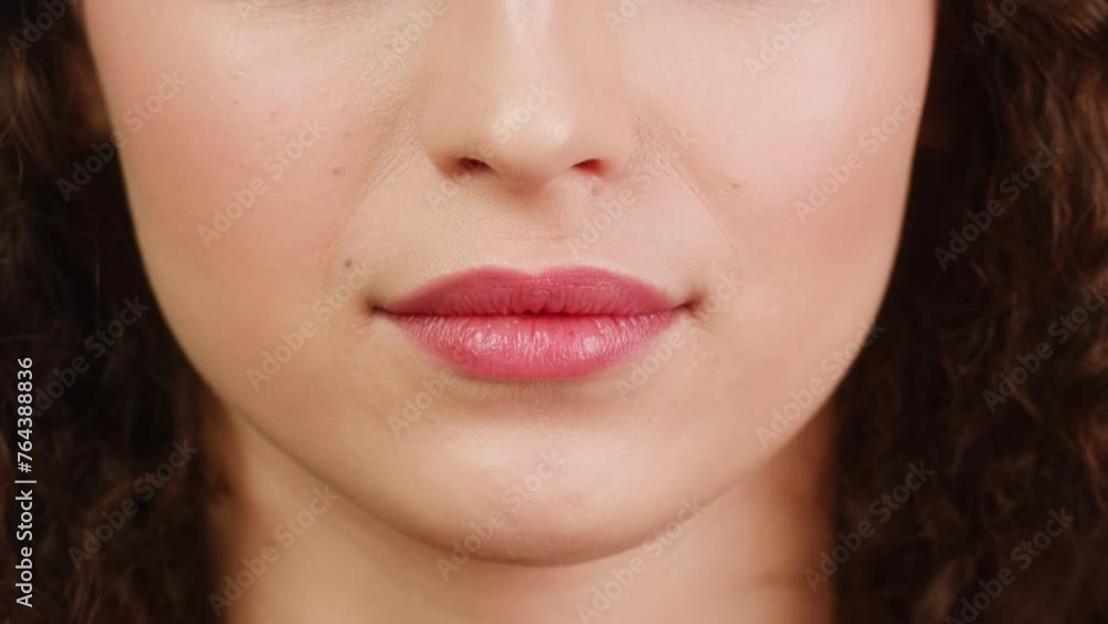 Close-up of young woman plump lips, moles on the face. Pink background. Nature beauty of female face skin Close-up of young woman plump lips, moles on the face. Pink background. Nature beauty of female face skin