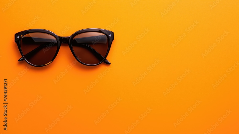 Sleek black sunglasses centered on a bright orange surface Sleek black sunglasses centered on a bright orange surface