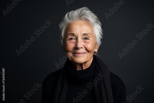 Portrait of a smiling senior woman on a dark background. Studio shot.
