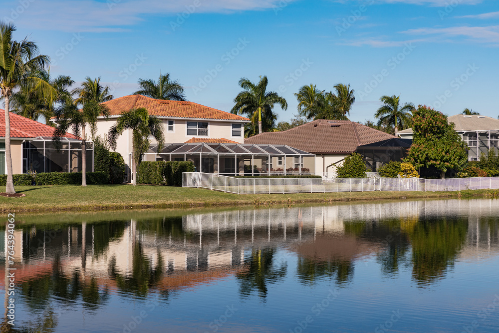 Typical concrete house on the shore of a lake in southwest Florida in the countryside with palm trees, tropical plants and flowers, lawn and pine trees. Florida.