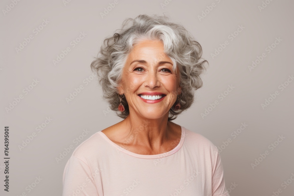 Portrait of a smiling senior woman with grey hair posing against grey background Portrait of a smiling senior woman with grey hair posing against grey background