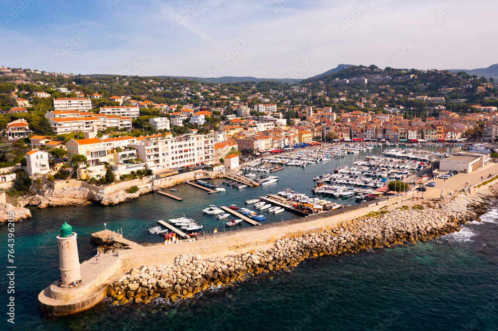 Picturesque aerial view of Cassis cityscape on Mediterranean coast overlooking marina with moored yachts and lighthouse on sunny autumn day, Southern France