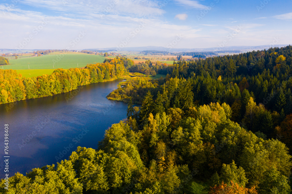 Aerial view of picturesque autumn river landscape with colored trees on sunny day