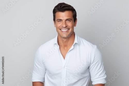 Portrait of handsome young man smiling at camera while standing against grey background