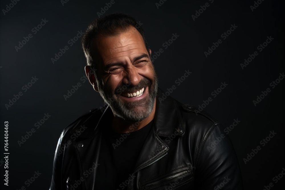 Portrait of a happy mature man in leather jacket on dark background