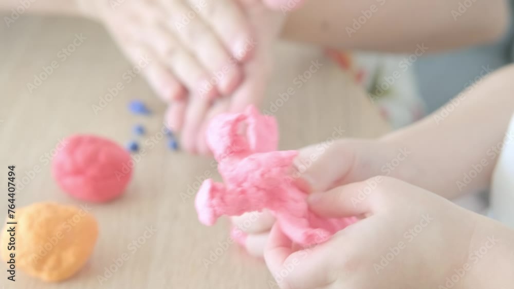 close-up plasticine toys in hands of toddler, small child, blonde girl 2 years old sculpts figures characters from colored dough, concept fine motor skills, tactile sensations, creativity close-up plasticine toys in hands of toddler, small child, blonde girl 2 years old sculpts figures characters from colored dough, concept fine motor skills, tactile sensations, creativity