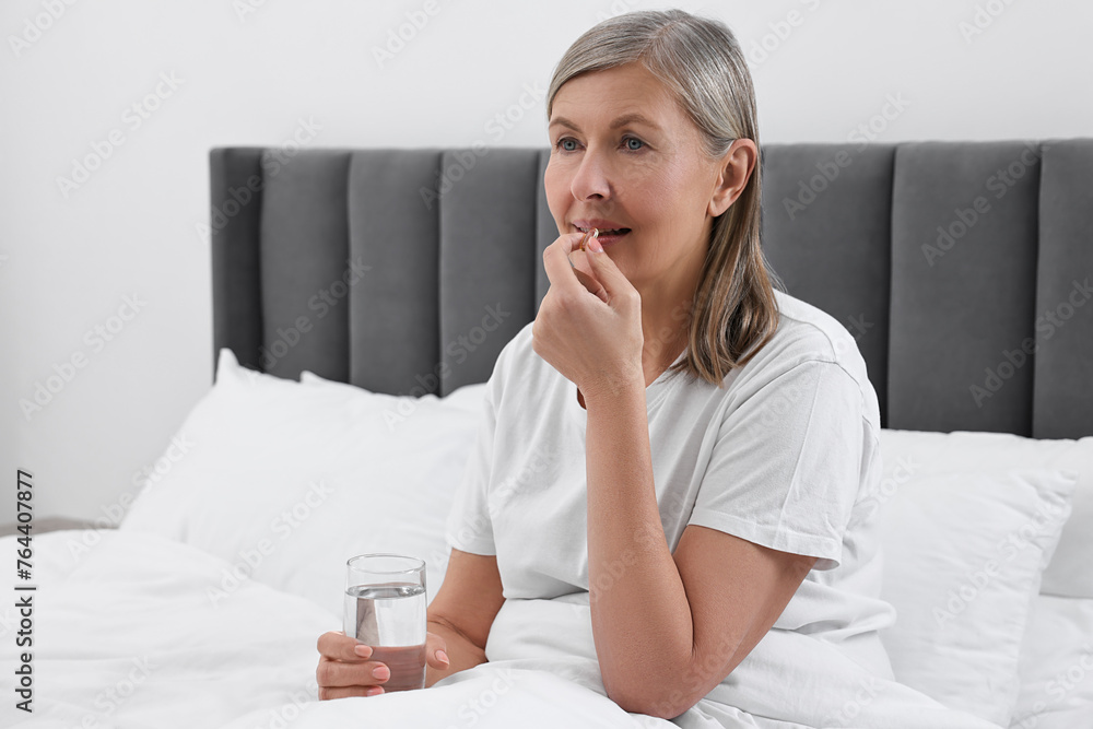 Beautiful woman taking vitamin pill in bedroom Beautiful woman taking vitamin pill in bedroom