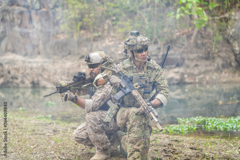 Soldiers in tactical gear aiming guns during a military exercise, showcasing teamwork and defense strategies.