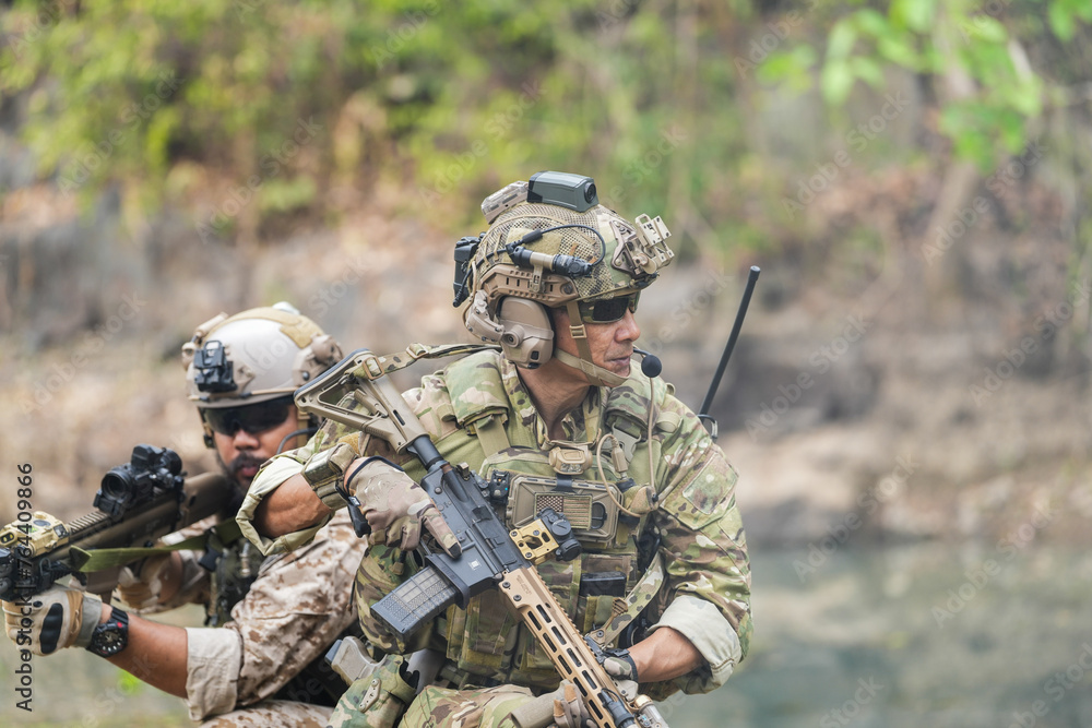 Fototapeta premium Soldiers in tactical gear aiming guns during a military exercise, showcasing teamwork and defense strategies.
