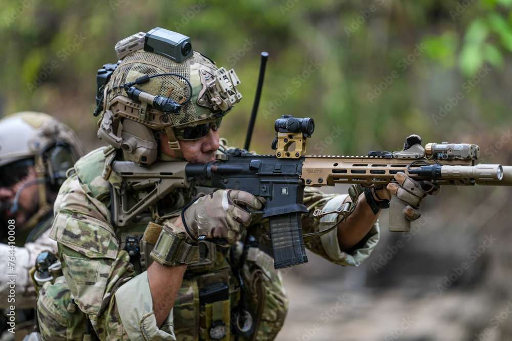 Fototapeta premium Soldiers in tactical gear aiming guns during a military exercise, showcasing teamwork and defense strategies.