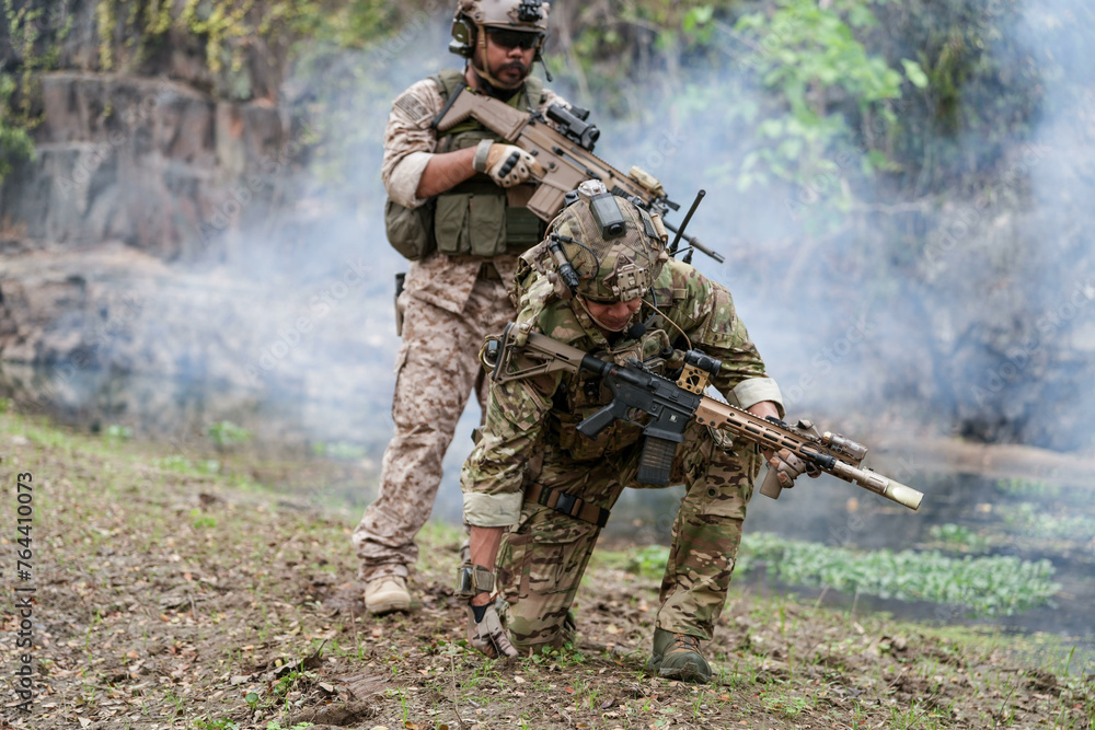 Fototapeta premium Soldiers in tactical gear aiming guns during a military exercise, showcasing teamwork and defense strategies.