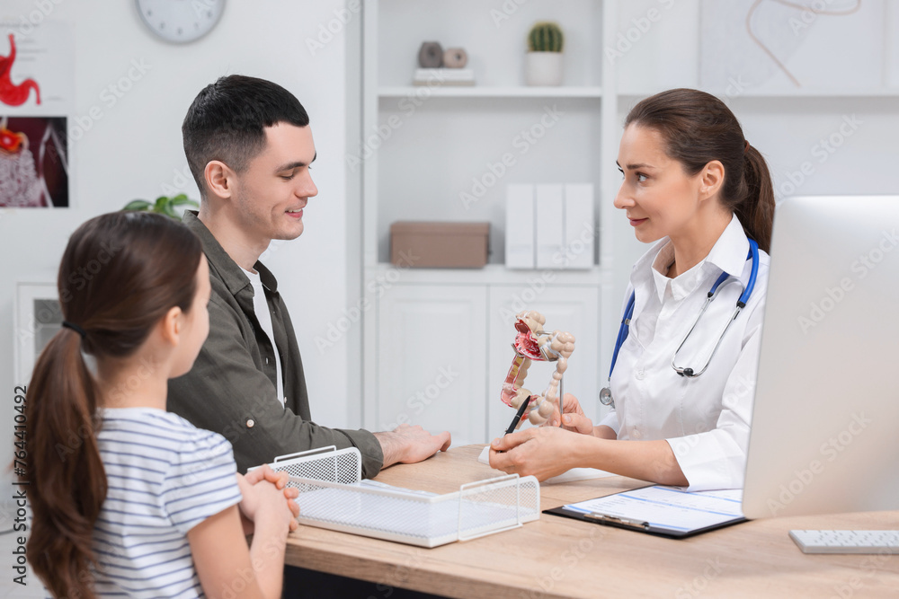 Gastroenterologist with model of intestine consulting man and his daughter in clinic Gastroenterologist with model of intestine consulting man and his daughter in clinic