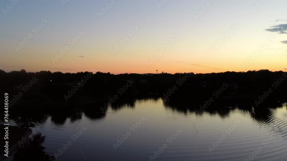 Aerial Backward Shot Of Rippled Pattern In Tranquil River Amidst Trees On Landscape Against Orange Sky During Sunset - Buckner, California Aerial Backward Shot Of Rippled Pattern In Tranquil River Amidst Trees On Landscape Against Orange Sky During Sunset - Buckner, California