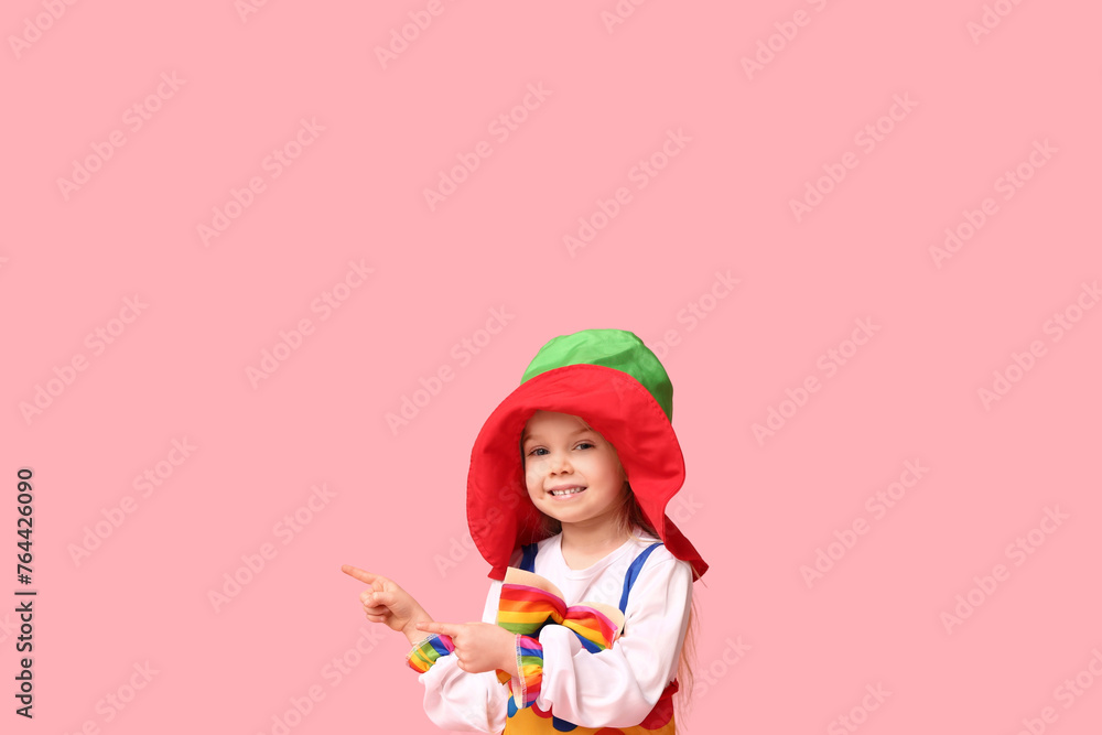 Little girl in clown costume and hat on pink background