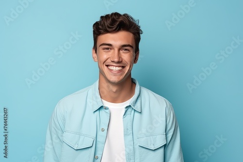 Portrait of a handsome young man smiling at camera on blue background
