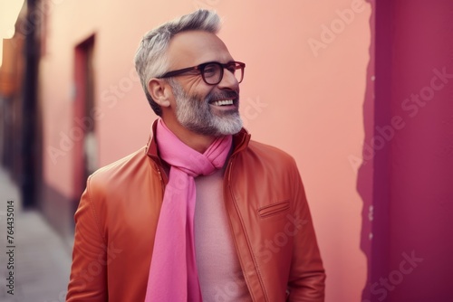 Portrait of a smiling senior man wearing glasses and a pink scarf in the city.