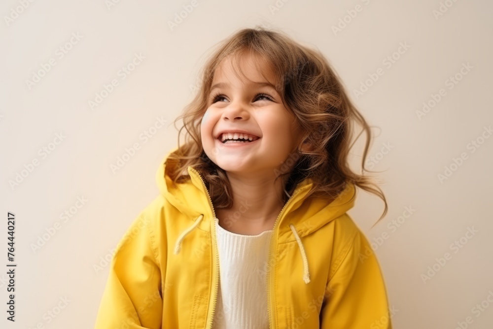 Portrait of a smiling little girl in a yellow jacket on a light background Portrait of a smiling little girl in a yellow jacket on a light background