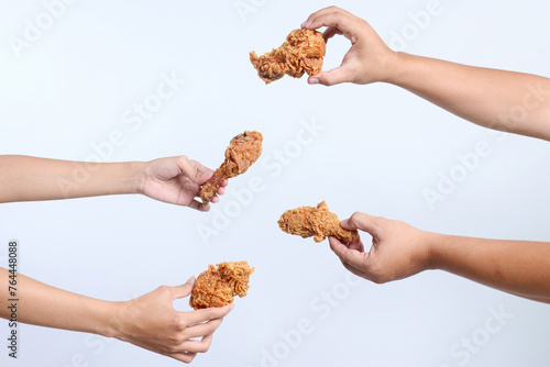 Portrait of many hands holding a piece of fried chicken isolated over white background photo