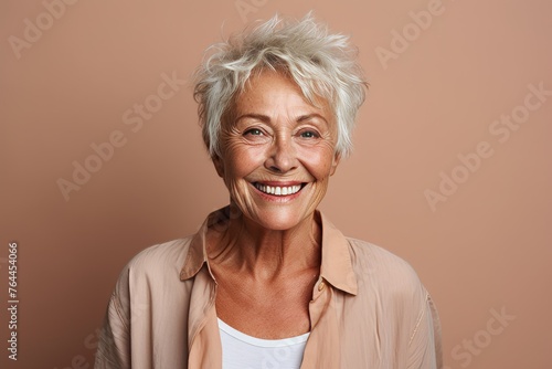 Portrait of a smiling senior woman on a beige background.