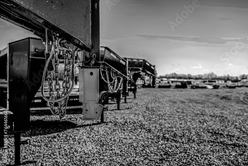 Selective focus on gooseneck trailer hitch with a row of flatbeds lined up. 
