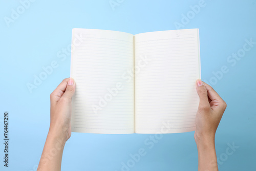 Hands holding a blank book ready with copy space ready for text, isolated on blue background, with clipping path