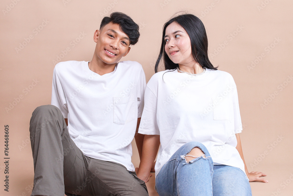 Young couple sitting on the floor wearing white blank t-shirt Young couple sitting on the floor wearing white blank t-shirt