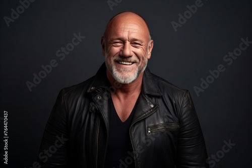Portrait of a happy senior man in leather jacket on dark background.