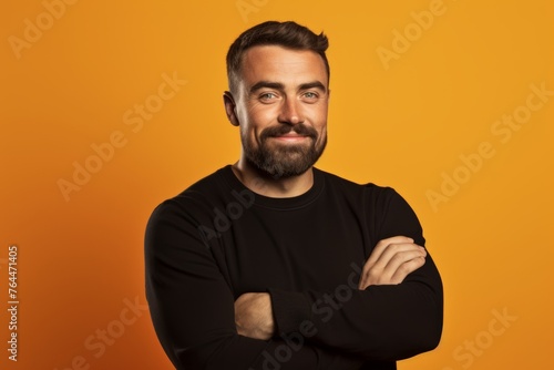 Portrait of a handsome bearded man with crossed arms on orange background